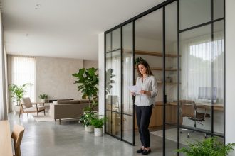 Cloison vitrée en acier noir séparant un bureau d'un salon dans un appartement moderne aux finitions béton et bois clair