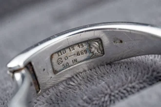 Gros plan sur un poinçon argent officiel frappé sur un bracelet en argent sterling posé sur un plateau de velours gris
